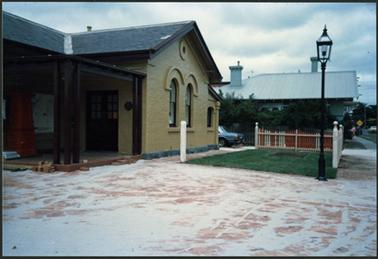 This view shows the freshly painted Old Post Office Museum, completed paving and grassed area with paling fence and street lamp