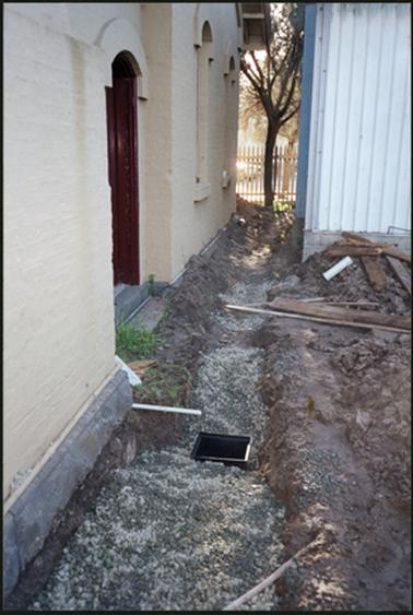 The image shows preparing to treat rising damp at the rear of the OPOM