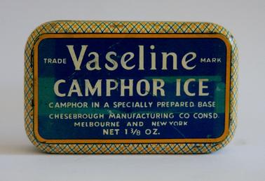 Small tin with lid.  Cream colour with blue/green lid with white writing.