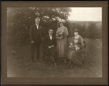 A Wedding group photo of four adults, Edwin (Ted) sitting and Alfred standing and two ladies