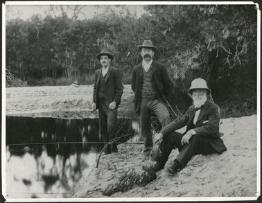 The image is of George Taylor Senior sittting on the banks of Balcombe Creek with his two sons standing by his side