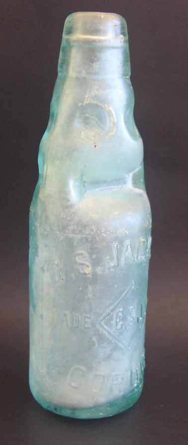 Clear green bottle with glass marble.  Heavy indentations in top third.  Raised lettering on surface of bottle.