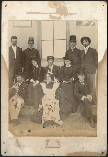A group photo of men and women in various costumes, inscription of the back of photo reads, back row Mr Grant, J. Jenkins, Mr Mason, C. Kirkpatrick, Mrs W. Grover, Mr Mellor, Miss Madge Ross, Mr Thompson, B. Kirkpatrick