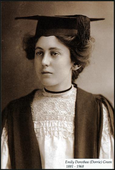 This photograph shows a young woman in cap and gown. She is wearing a beautiful lace topped dress, with a string of pearls around her neck