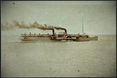 This image shows a Steam Ship in motion. It has two funnels with smoke streaming from both. The Bay looks quite calm. 