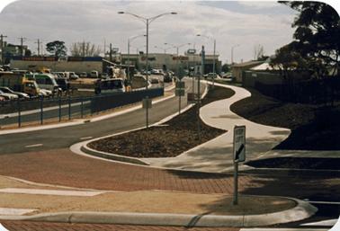 A newly developed roadway system with commercial buildings, apparently recent, in the background.