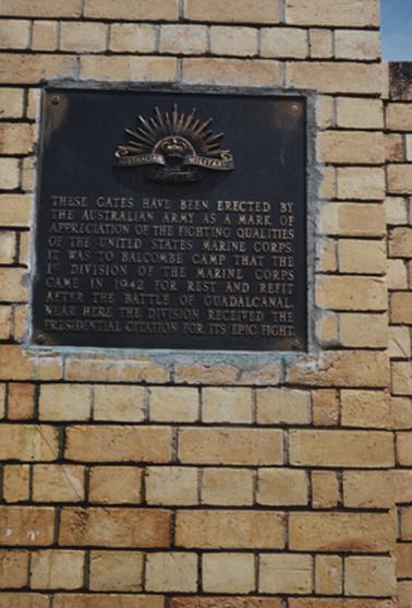 This shows a bronze plaque in a blond brick wall. The insignia at the head of the plaque is a sun rise with a crown at the centre, and the words Australian Military Forces.