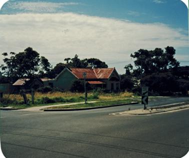 A single storied house and outbuildings situated on a wide road (Barkly Street) near a corner block. The house appears to be quite old with a mottled terra cotta coloured roof. It is surrounded by several mature trees and is beside a vacant grassed block on the corner of Barkly Street and Railway Parade.