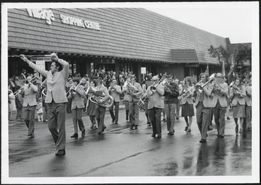 The image shows the Mornington Band playing as they walk past the Village Shopping Centre on Australia Day 1978