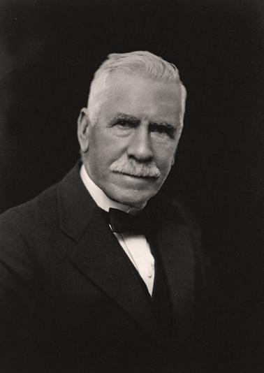 Head and shoulders photograph of an elderly man with white hair dressed in a dinner suit.