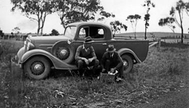 Utility truck in paddock at Herb Downward’s farm at Moorooduc. Two men identified as Bernard Callanan & Herb Downward seated on and beside the ute.