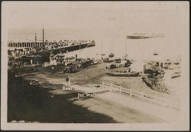 This is a wonderful view of the Pier showing it crowded with people, and a boat leaving Mornington for Melbourne. There are cars parked and people strolling wearing Edwardian dress.