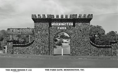 This is a photo of the Park Gate, which is made of rock. It has turrets on the top for decoration. The signage is in large white letters stating “Mornington Park”. to the left of the gate is a large sign “Welcome to Mornington, carnivals bazaar, from Xmas to ANA. 