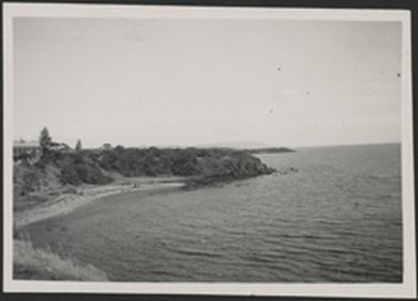 This is a view of the sea and foreshore taken from a high point on the land. There is a large impressive house on the left of the photo.
